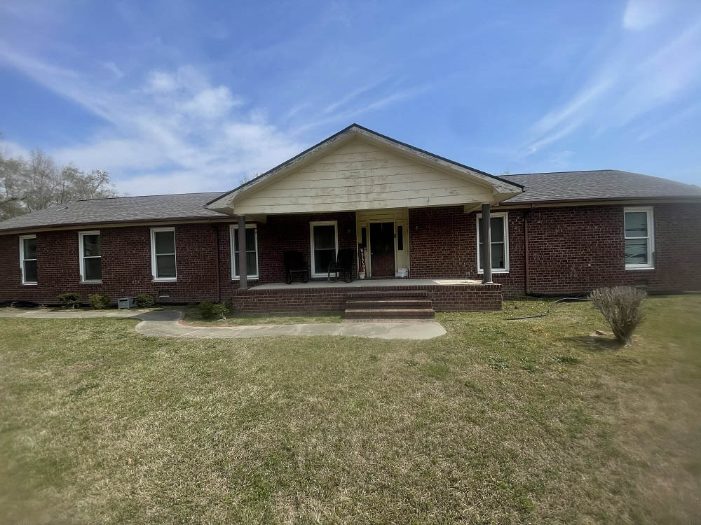 Full front lawn view of Eastover brick ranch home before repainting